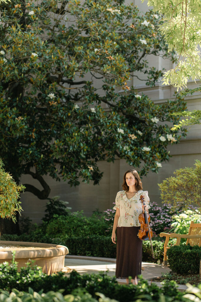 Emily posing with her violin beneath the trees at the National Gallery of Art