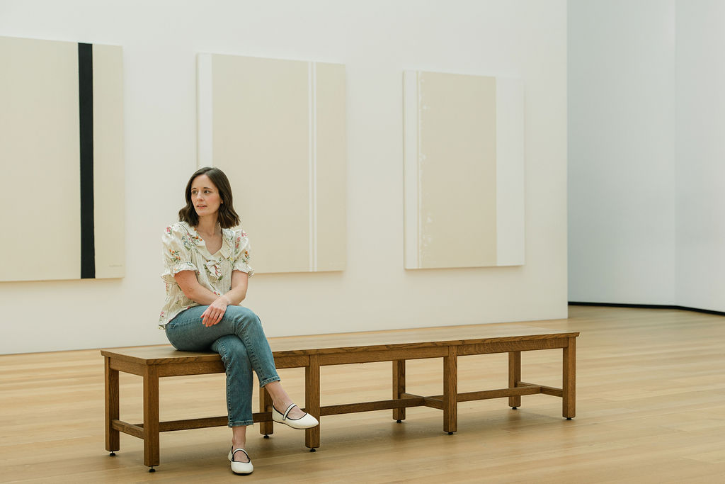 Portrait of Emily on a bench against a backdrop of museum artwork in Washington, DC