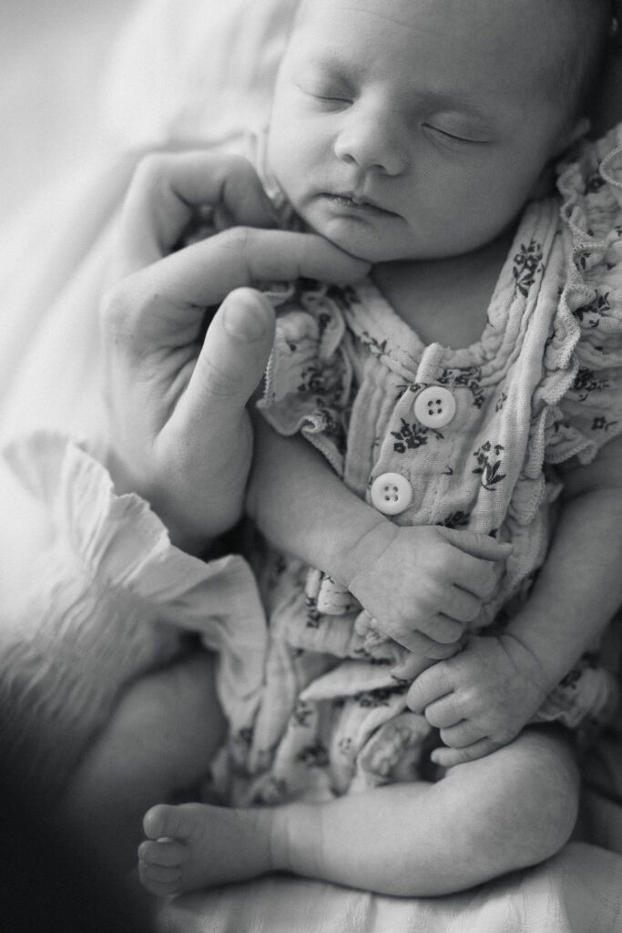 Newborn baby girl resting in her mother's hands during an in-home session