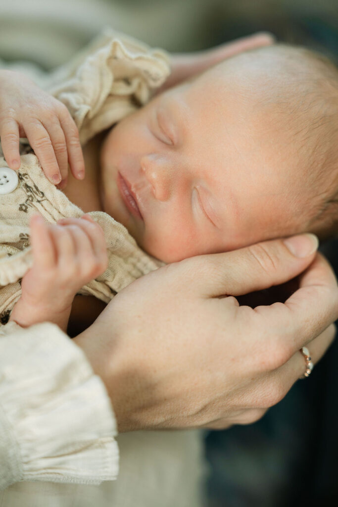 Close-up of a sleeping newborn baby being gently touched by a parent