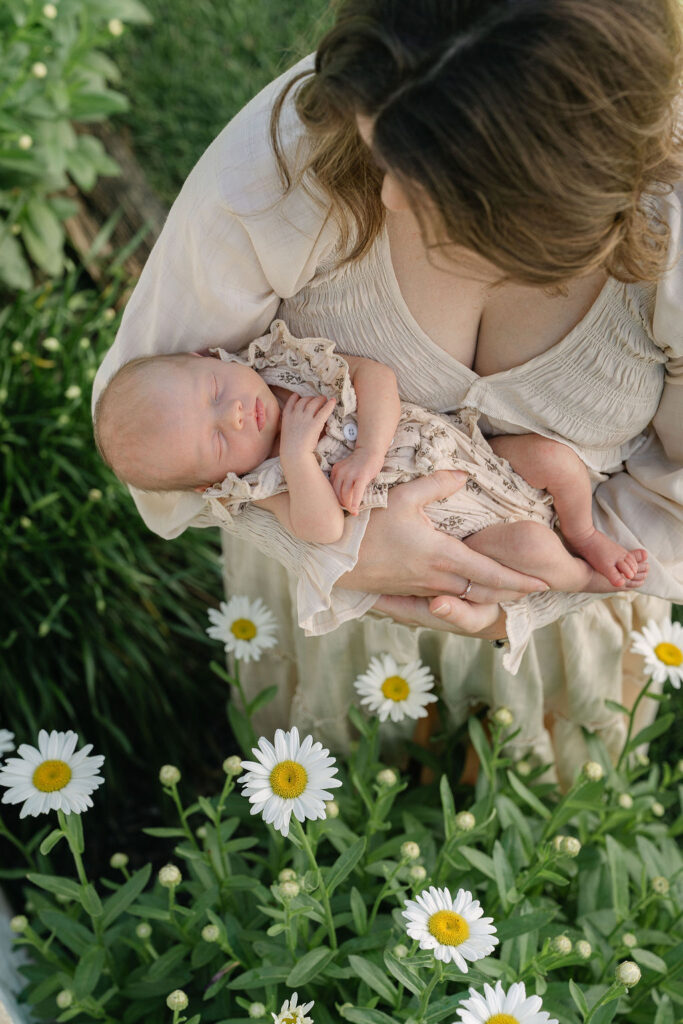 Mother holding her newborn baby outdoors during a family session