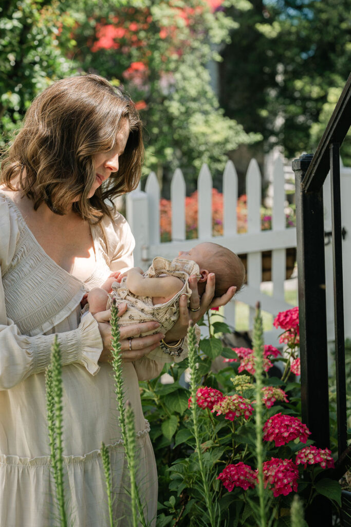 Mother holding her newborn baby outdoors in a garden