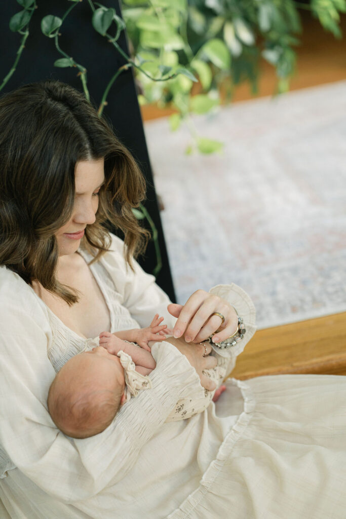 Mother looking down at her newborn baby during an in-home session