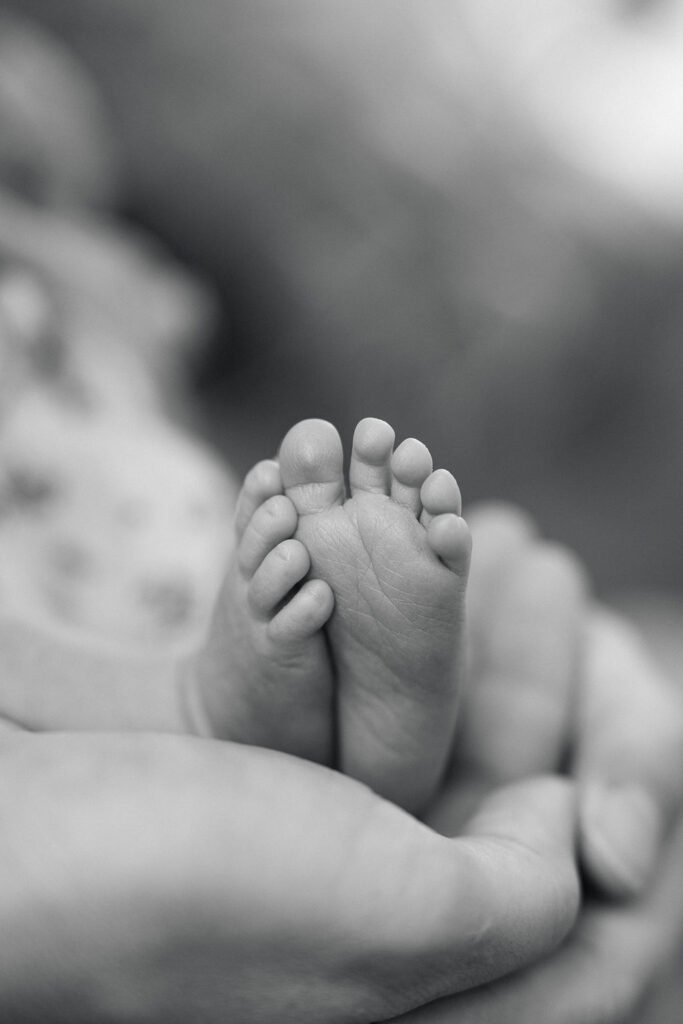Close-up of a parent gently holding a newborn baby's tiny feet