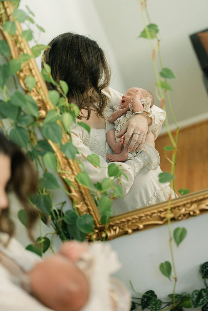 Mother gently holding her newborn baby during an in-home session
