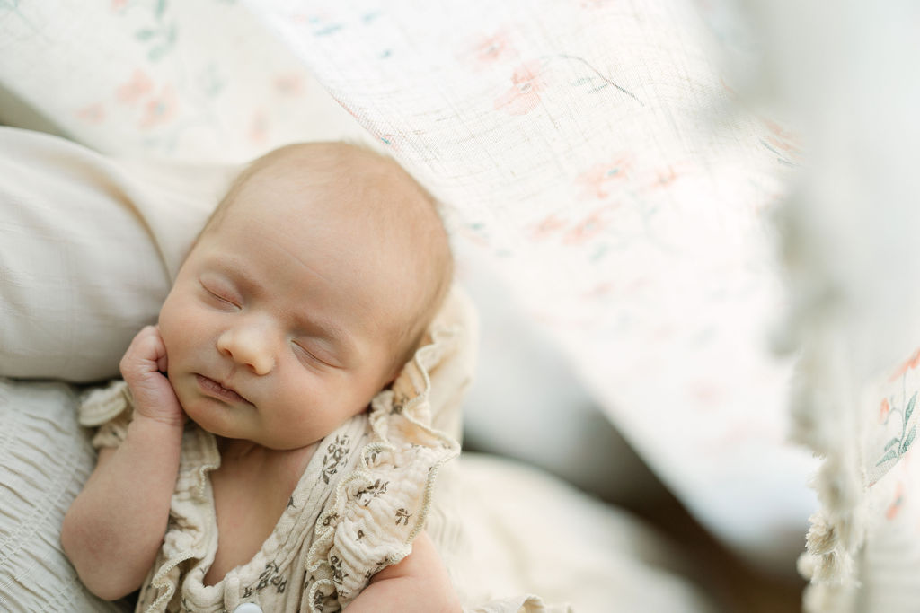 Sleeping newborn baby girl lying on a soft floral blanket
